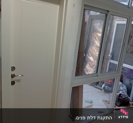 דלת לבנה עם ידית מתכת ליד חלון זכוכית